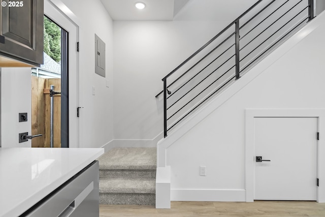 stairway featuring electric panel, wood finished floors, baseboards, and recessed lighting