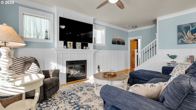 2781 SW Coast Ave, Lincoln City, OR 97367 - living room featuring a ceiling fan, wood finished floors, a wainscoted wall, stairway, and a glass covered fireplace