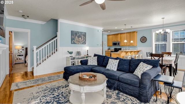 2781 SW Coast Ave, Lincoln City, OR 97367 - living area featuring crown molding, light wood-type flooring, ceiling fan, a chandelier, and stairway