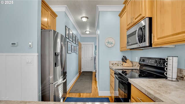 2781 SW Coast Ave, Lincoln City, OR 97367 - kitchen with appliances with stainless steel finishes, light countertops, ornamental molding, light wood-style floors, and light brown cabinets