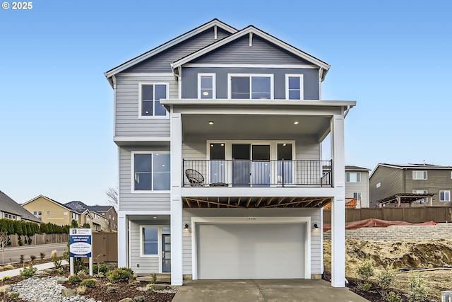 view of front of home featuring driveway, an attached garage, fence, and a balcony