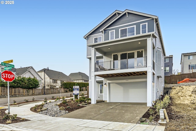 view of front of property featuring a garage, concrete driveway, a balcony, a residential view, and fence