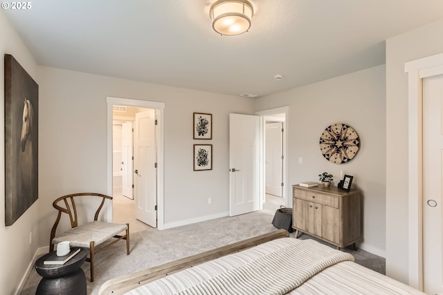 bedroom with baseboards, connected bathroom, visible vents, and light colored carpet