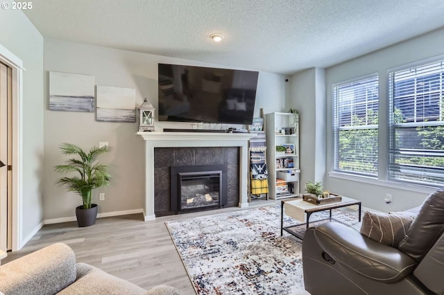 768 NE 70th Ave, Hillsboro, OR 97124 - living area with light wood-style flooring, a textured ceiling, a tile fireplace, and baseboards
