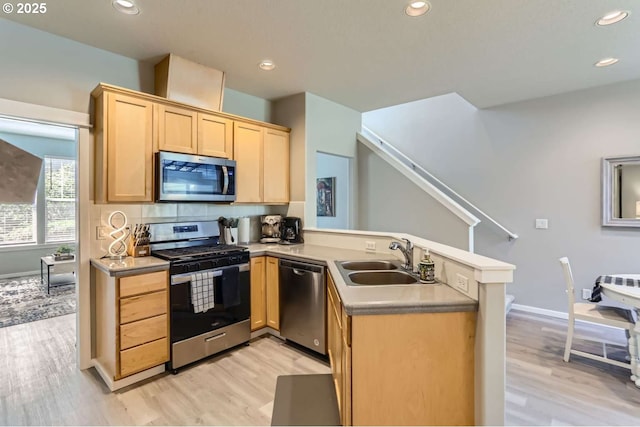 768 NE 70th Ave, Hillsboro, OR 97124 - kitchen with appliances with stainless steel finishes, a sink, light brown cabinets, a peninsula, and light wood finished floors