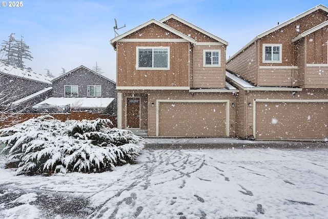 snow covered back of property with a garage