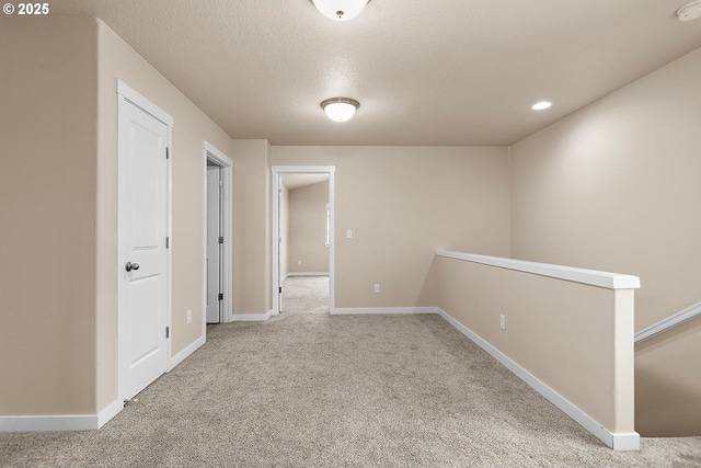 hall featuring carpet and a textured ceiling