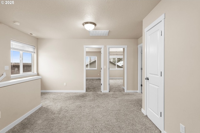 empty room with light colored carpet, plenty of natural light, and a textured ceiling