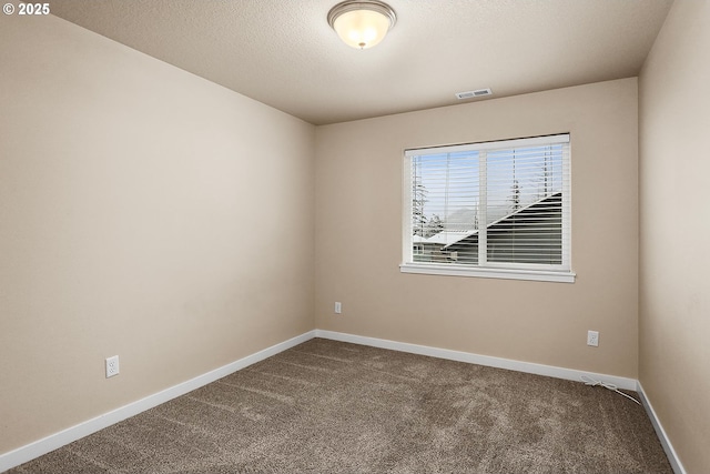 carpeted empty room featuring a textured ceiling