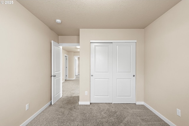 unfurnished bedroom featuring light colored carpet, a closet, and a textured ceiling