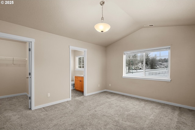 unfurnished bedroom with lofted ceiling, a spacious closet, light colored carpet, and a closet