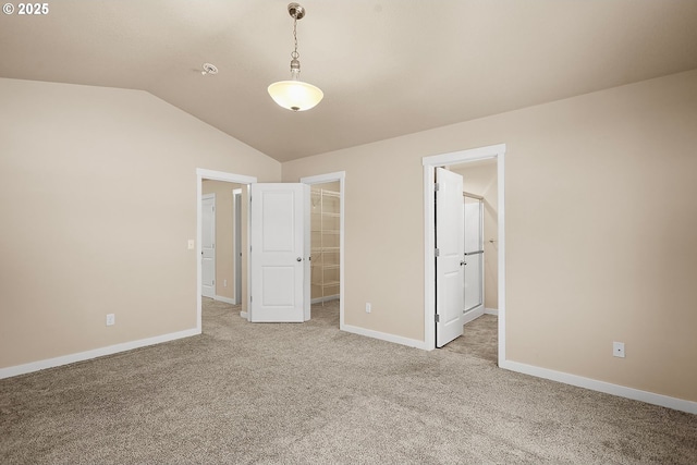 unfurnished bedroom with a closet, a spacious closet, vaulted ceiling, and light carpet