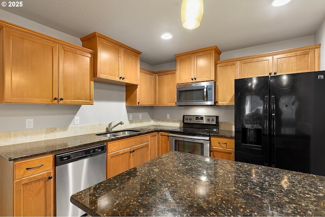 kitchen with appliances with stainless steel finishes, sink, and dark stone countertops