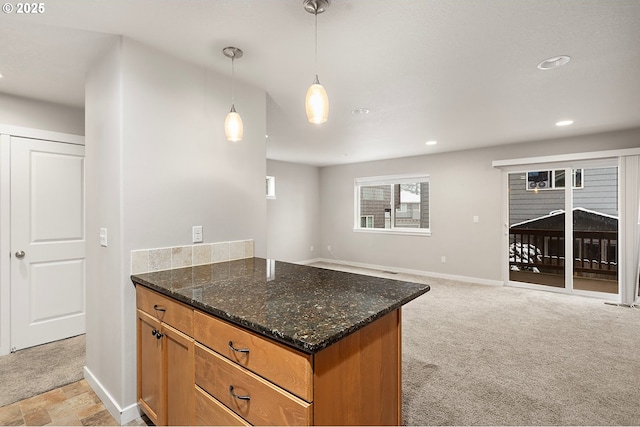 kitchen featuring decorative light fixtures, light colored carpet, and dark stone counters