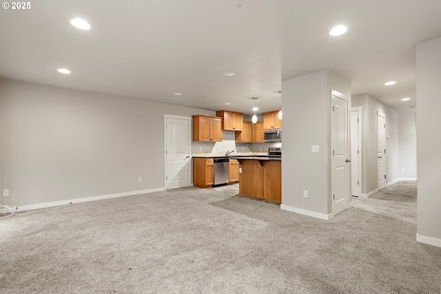 kitchen featuring pendant lighting, a kitchen bar, stainless steel appliances, a kitchen island, and light colored carpet