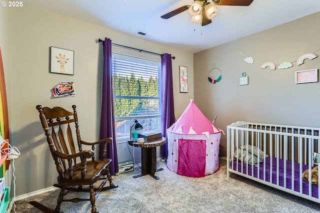 carpeted bedroom featuring a nursery area and ceiling fan