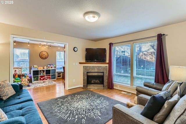 living room with a tile fireplace and hardwood / wood-style floors