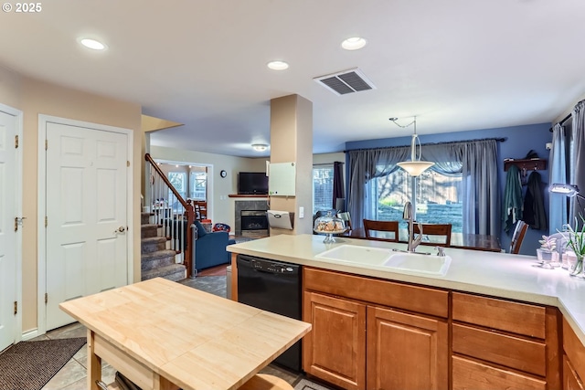 kitchen featuring pendant lighting, dishwasher, a kitchen island with sink, sink, and light tile patterned floors