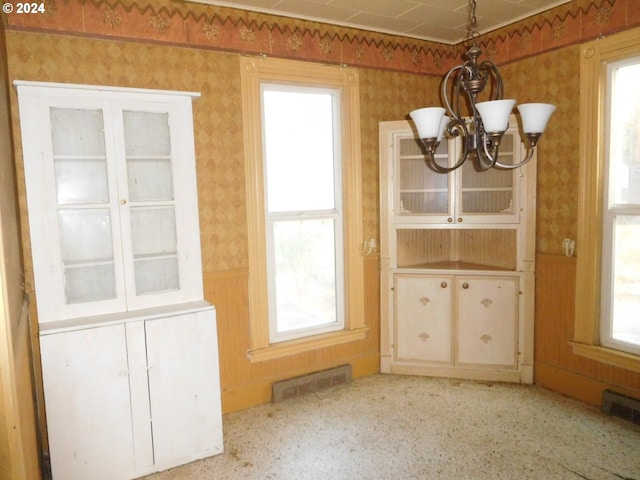 unfurnished dining area featuring an inviting chandelier and a healthy amount of sunlight