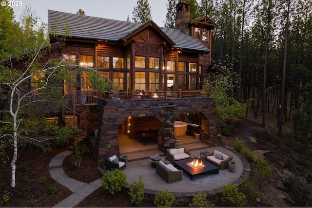 rear view of house with an outdoor living space with a fireplace and a patio