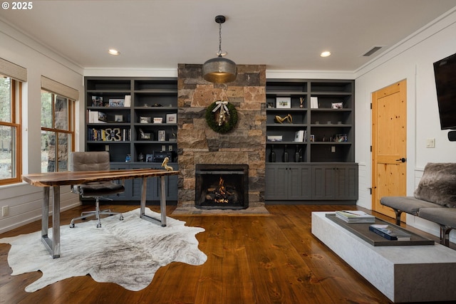 home office with built in shelves, ornamental molding, a stone fireplace, and dark hardwood / wood-style flooring