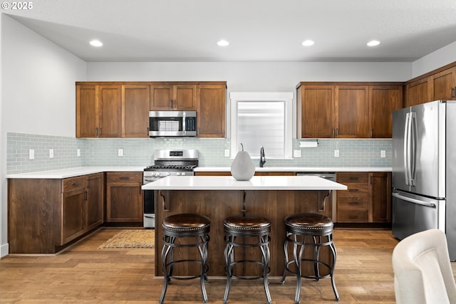16849 SW Friendly Ln, Beaverton, OR 97007 - kitchen with stainless steel appliances, a breakfast bar, light wood-style flooring, light countertops, and recessed lighting