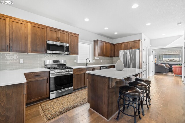 16849 SW Friendly Ln, Beaverton, OR 97007 - kitchen with appliances with stainless steel finishes, a breakfast bar, light countertops, a sink, and recessed lighting