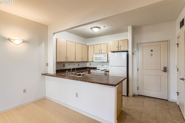 kitchen featuring light brown cabinetry, sink, white appliances, and kitchen peninsula