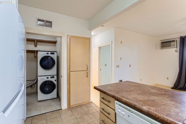 laundry area featuring light tile patterned floors, an AC wall unit, and stacked washer / dryer