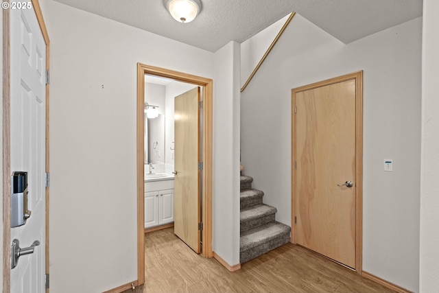 6309 NE 45th Ave, Portland, OR 97218 - hallway featuring light wood-type flooring, a sink, stairway, and a textured ceiling