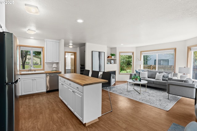 6309 NE 45th Ave, Portland, OR 97218 - kitchen with butcher block countertops, stainless steel appliances, open floor plan, white cabinets, and a textured ceiling