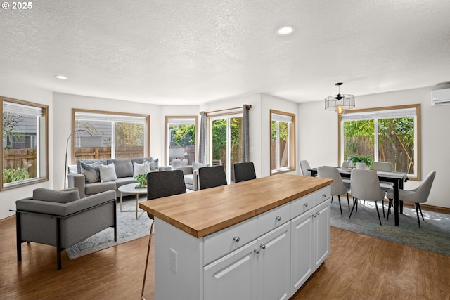 6309 NE 45th Ave, Portland, OR 97218 - kitchen with butcher block counters, a textured ceiling, wood finished floors, white cabinets, and recessed lighting