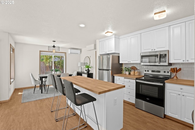 6309 NE 45th Ave, Portland, OR 97218 - kitchen with appliances with stainless steel finishes, wooden counters, light wood-type flooring, white cabinets, and a textured ceiling