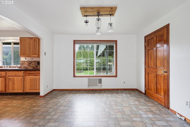 unfurnished dining area with stone finish floor, baseboards, a wall mounted air conditioner, and a sink