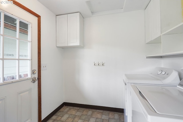 washroom with baseboards, washer and clothes dryer, stone finish floor, attic access, and cabinet space