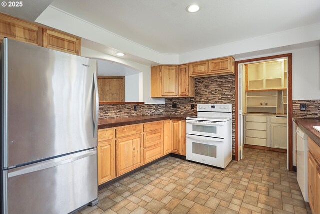 kitchen featuring stone finish flooring, dark countertops, tasteful backsplash, recessed lighting, and white appliances