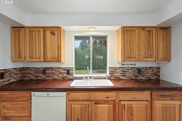 kitchen featuring dark countertops, a sink, tasteful backsplash, and white dishwasher