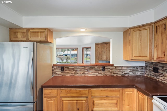 kitchen with dark countertops, tasteful backsplash, freestanding refrigerator, and white range with electric stovetop