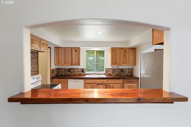 kitchen with arched walkways, white appliances, and dark countertops