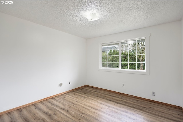 empty room with a textured ceiling, baseboards, and wood finished floors