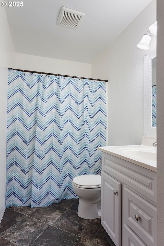 full bathroom featuring vanity, a shower with shower curtain, visible vents, stone finish flooring, and toilet