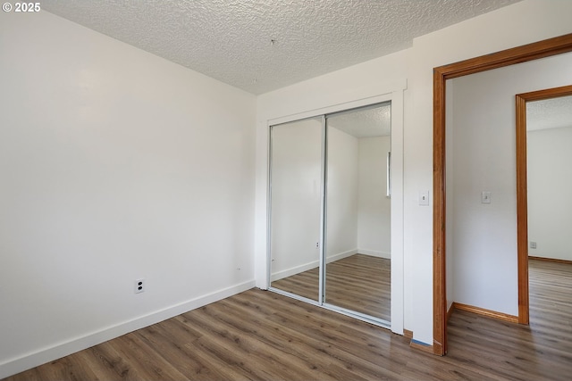 unfurnished bedroom with a closet, baseboards, and wood finished floors