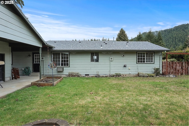 rear view of property featuring fence, roof with shingles, a vegetable garden, a yard, and a patio area