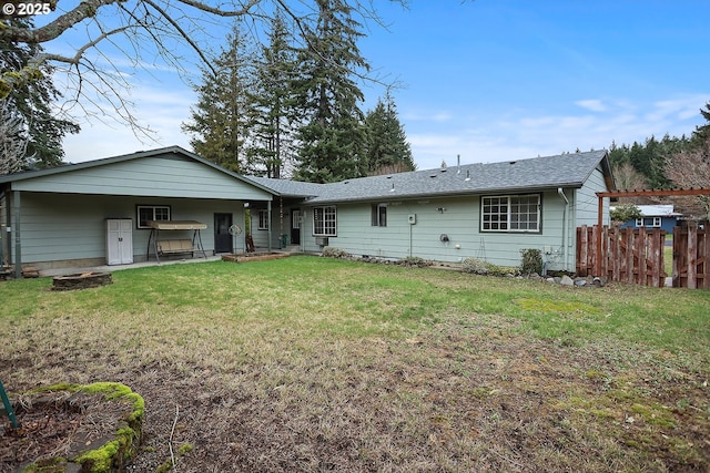 back of property with fence, a lawn, and a shingled roof