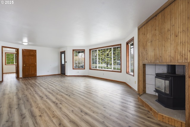 unfurnished living room with baseboards, wood finished floors, and a wood stove