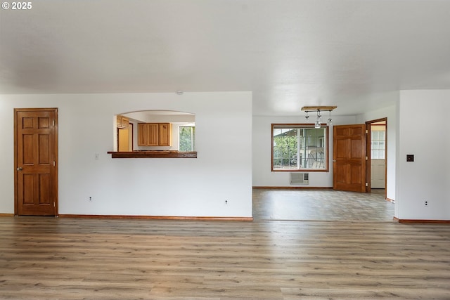 unfurnished room featuring baseboards, a wall unit AC, and wood finished floors