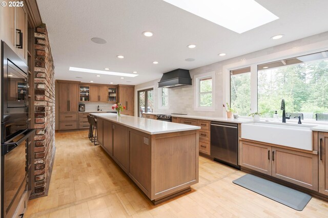 18020 SE 370th Ave, Sandy, OR 97055 - kitchen featuring appliances with stainless steel finishes, a sink, custom range hood, a kitchen island, and light wood-type flooring