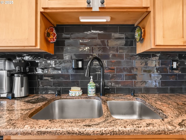 kitchen featuring light stone counters, tasteful backsplash, and a sink