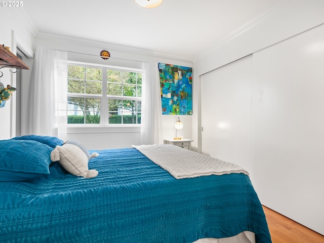 bedroom featuring a closet, wood finished floors, and ornamental molding