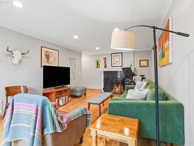 living area with a fireplace, wood finished floors, and ornamental molding